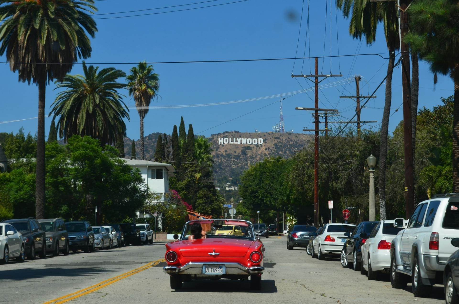 A red car driving down a street in West Hollywood, Los Angeles