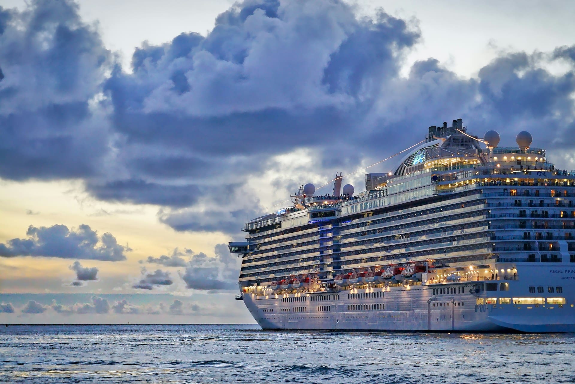 A side view of a cruise ship sailing into the sunset.