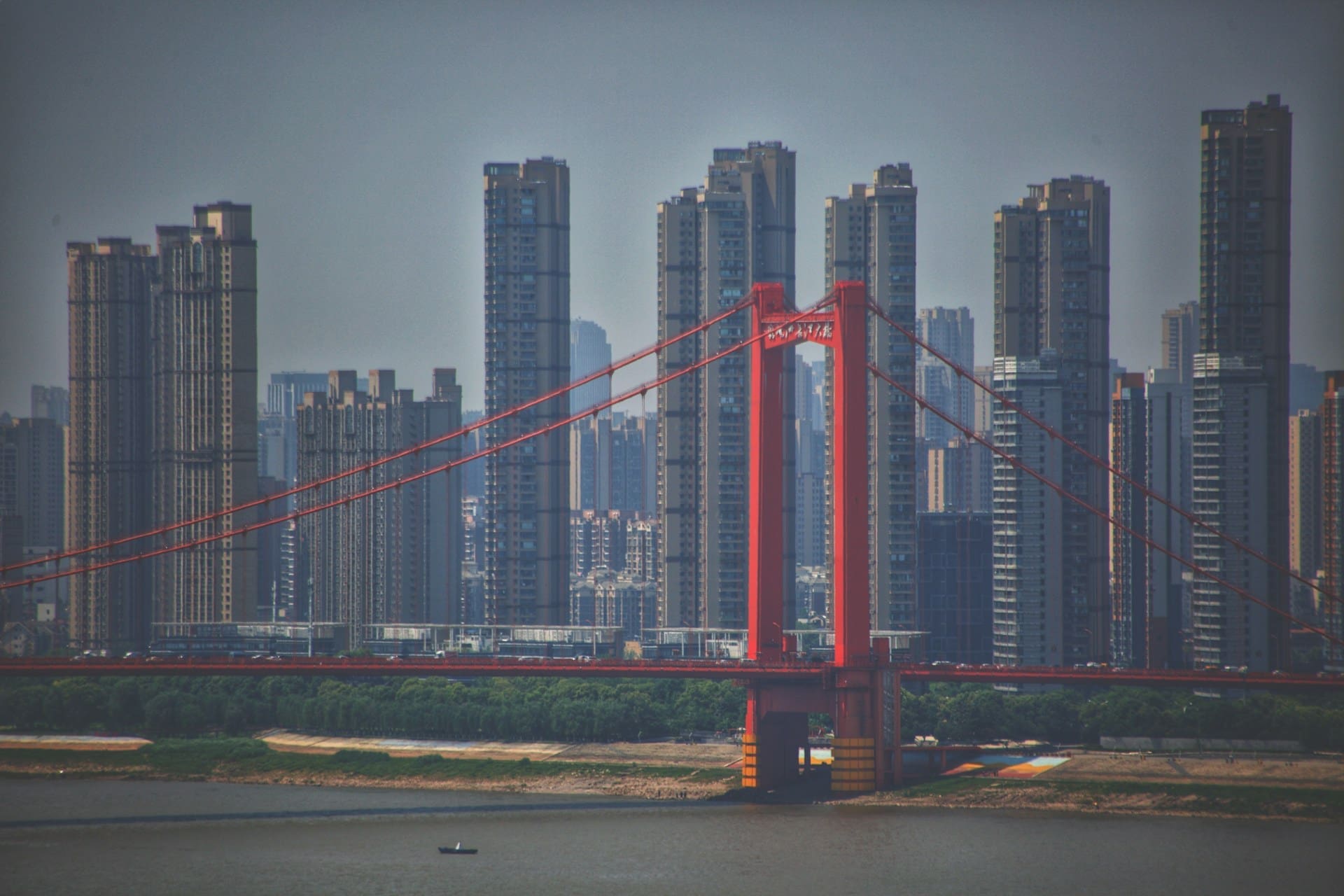 An image of tall buildings behind a bridge in Wuhan, China.
